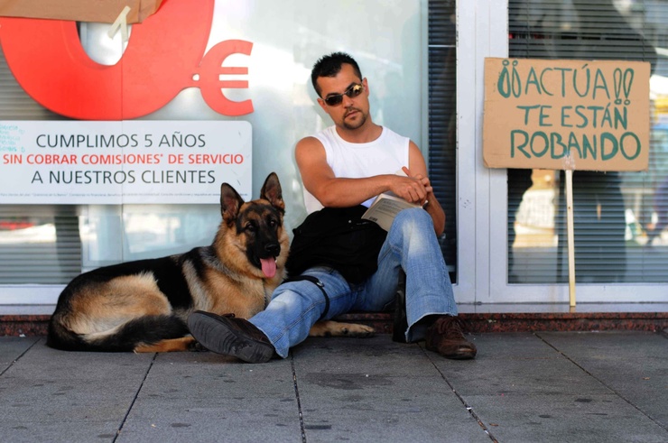 Un home protesta co seu can perante unha entidade financeira en Vigo 