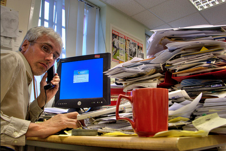Un traballador nunha oficina falando por teléfono diante dun ordenador 