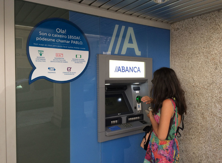 Muller sacando diñeiro dun caixeiro automático do banco ABANCA.