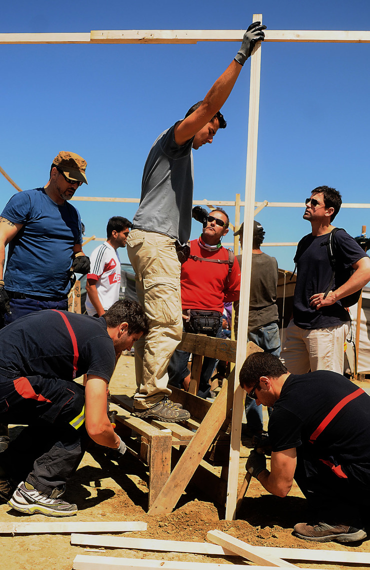 Bombeiros voluntarios erguen unha estrutura no campo de Idomeni para protexer os refuxiados dos raios de sol 