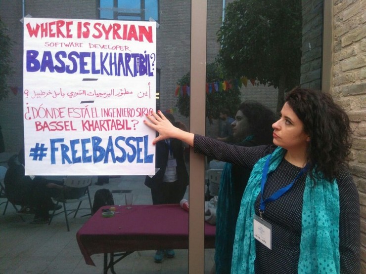 Leila Nachawati Rego sinala un cartel que pide a liberdade do activista sirio e programador de código aberto Bassel Khartabil 