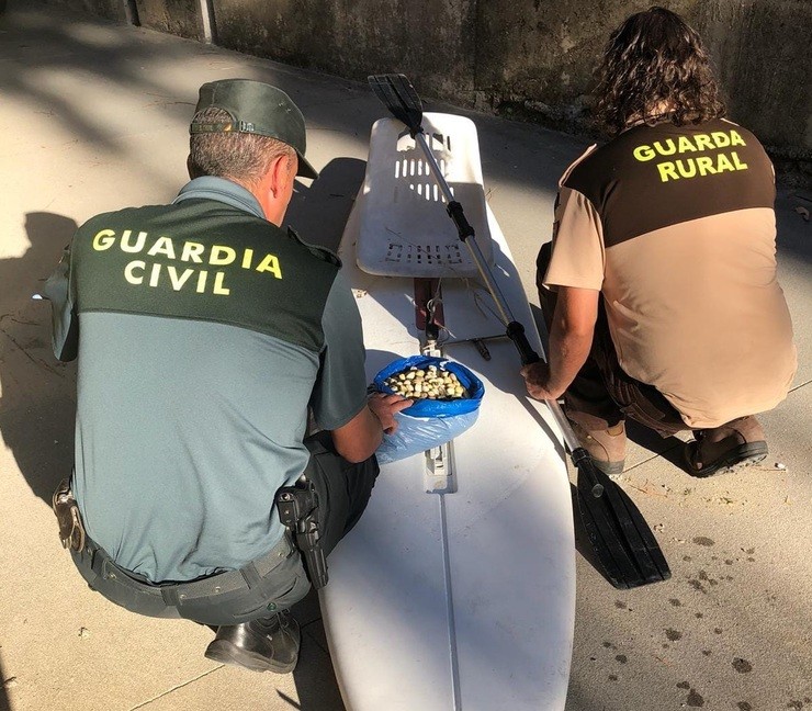 Axentes da Garda Civil, coa táboa de surf e o marisco incautado / Garda Civil.