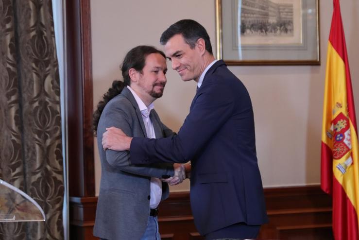 Pedro Sánchez e Pablo Iglesias abrázanse no Congreso dos Deputados despois de asinar o principio de acordo para compartir un goberno de coalición 