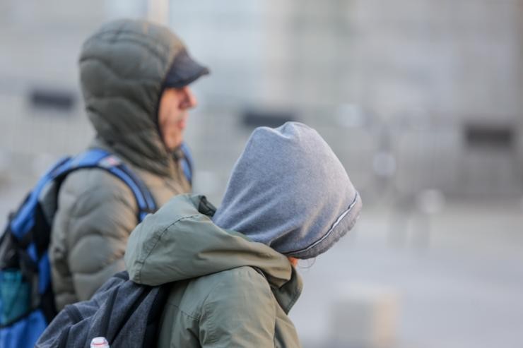 Dous mozos protéxense do frío con abrigos e gorros