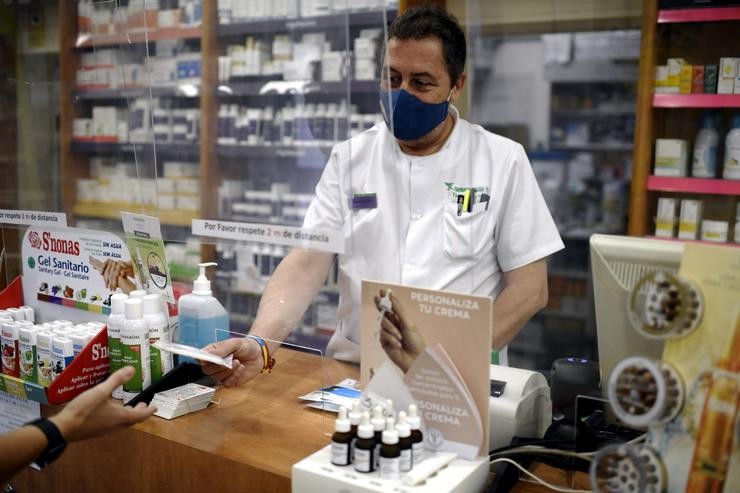 Un farmacéutico entrega a un cliente una das máscaras KN95 que recibiu na súa farmacia. Óscar Canas - Europa Press 