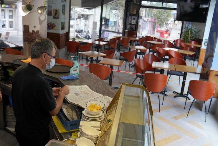 Un camareiro le un xornal no interior do seu bar. Álvaro Ballesteros - Europa Press