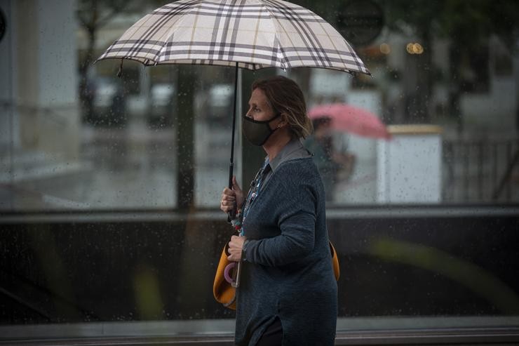 Unha muller protéxese baixo o seu paraugas durante unha xornada de choiva. En Sevilla (Andalucía, España), a 22 de outubro de 2020.. María José López - Europa Press