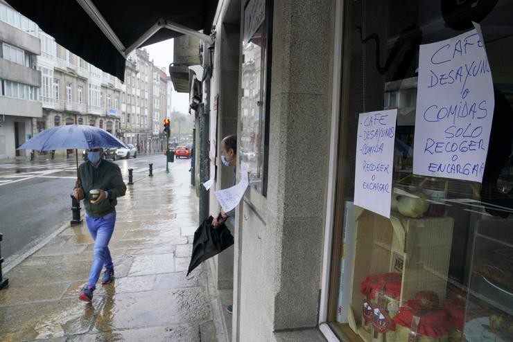 Un home pasa á beira dun establecemento pechado pola Covid en Santiago 