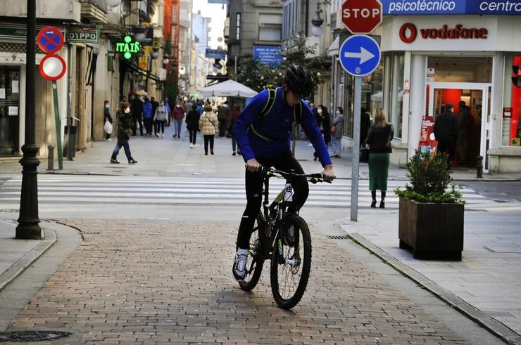 Unha persoa circula en bicicleta por unha vía do centro o mesmo día en que se levanta o peche perimetral do municipio e reábrese a hostalaría, no Carballiño / Rosa Veiga - Europa Press - Arquivo. / Europa Press