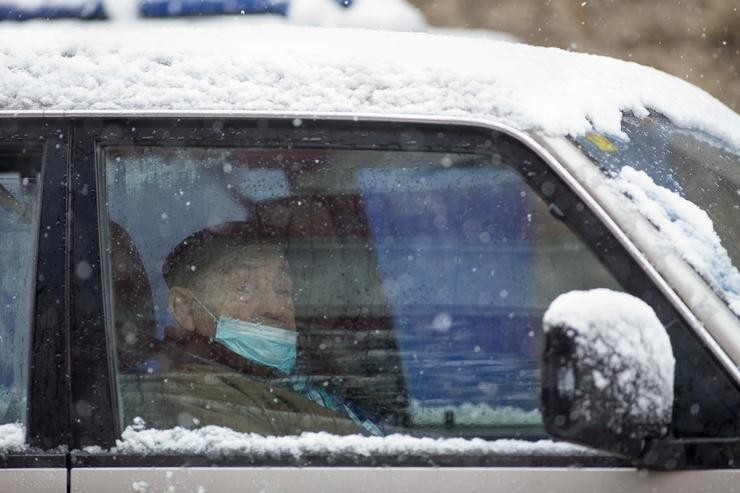 Un ancián con máscara permanece no seu vehículo durante a nevada en Becerrea, en Lugo. Carlos Castro - Europa Press 