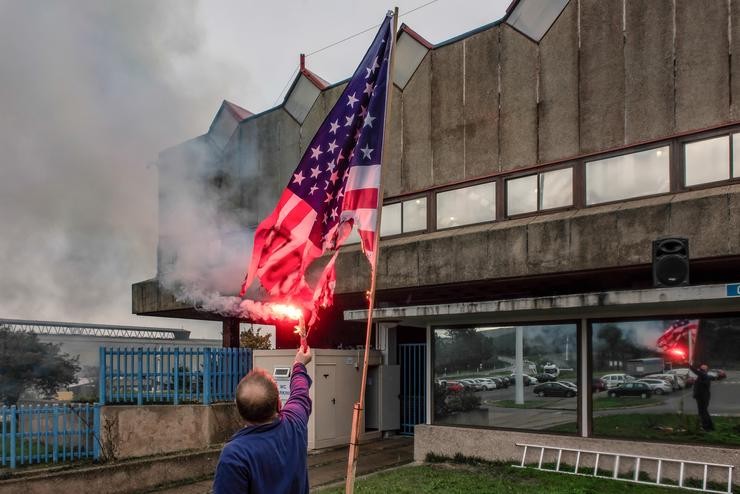 Un traballador de Alcoa San Cibrao queima unha bandeira de Estados Unidos diante da factoría 