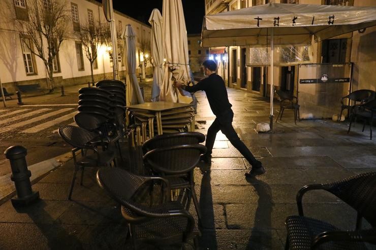 Un camareiro recolle a terraza do seu establecemento á hora do peche tras as medidas ordenadas pola crise do Covid-19, en Santiago de Compostela, Galicia, (España), a 6 de novembro. A hostalaría permanece pechada desde as 00,00 horas deste s. Álvaro Ballesteros - Europa Press