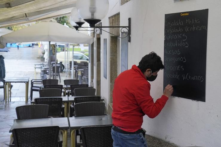 Un home escribe na lousa dun mesón, en Santiago de Compostela, A Coruña, Galicia (España), a 4 de decembro de 2020. Hoxe reábrese a hostalaría en toda Galicia, aínda que en distinto grao en función dos datos dos contagios de coronavirus, e. Álvaro Ballesteros - Europa Press / Europa Press