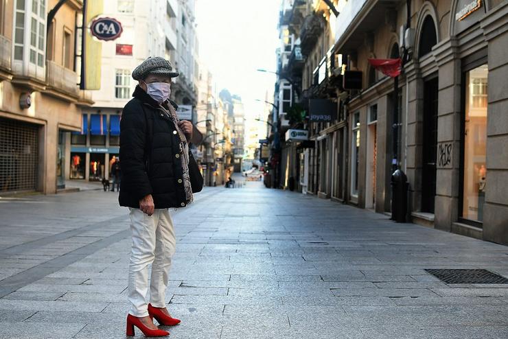 Muller con máscara na rúa do Príncipe, en Vigo, completamente baleira en pleno sábado por mor do coronavirus 