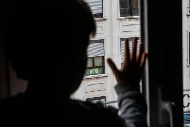 Unha crianza mirando pola ventá durante o confinamento.