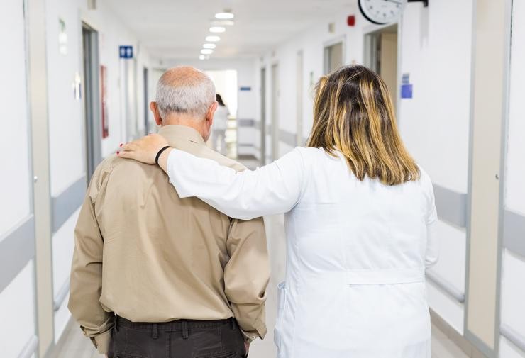 Un profesional sanitario acompaña a unha persoa maior nun hospital. MÁXIMO GARCÍA DA PAZ-FUNDACIÓN A CAIXA