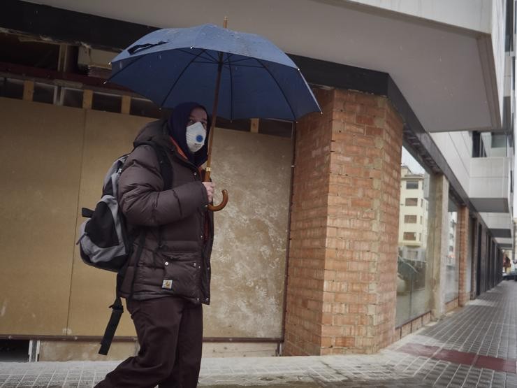 Un home con máscara camiña protexéndose cun paraugas pola choiva  durante o Martes Santo e a cuarta semana do estado de alarma decretado polo Goberno pola crise do coronavirus, en Pamplona/Navarra (España) a 7 de abril de 2020.. Eduardo Sanz - Europa Press / Europa Press