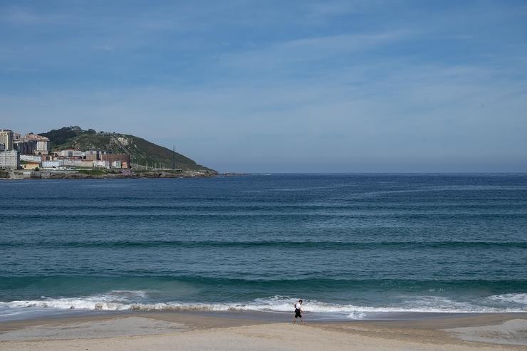 Unha persoa pasea pola praia do Orzán no segundo día en que o Goberno permite saír a facer deporte de forma individual e pasear con outra persoa. M. Dylan - Europa Press 