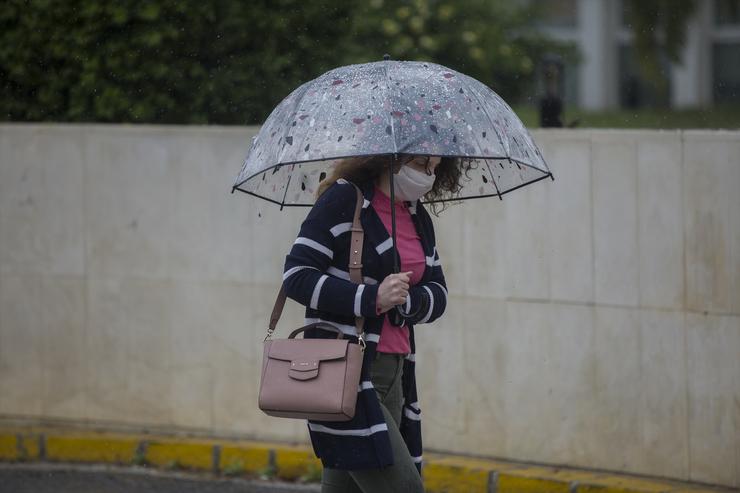 Unha muller con paraugas e máscara, durante a alerta amarela por choiva. María José López - Europa Press