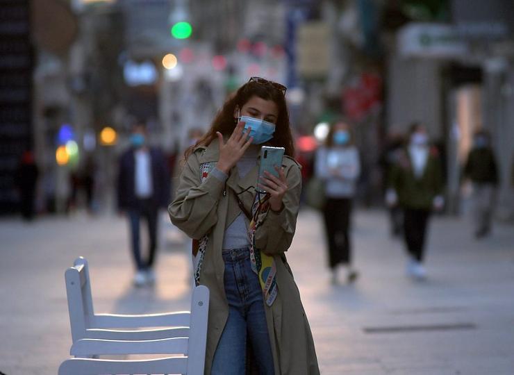 Unha rapaza pasea coa máscara posta pola rúa de Príncipe, en Vigo © Miguel Núñez