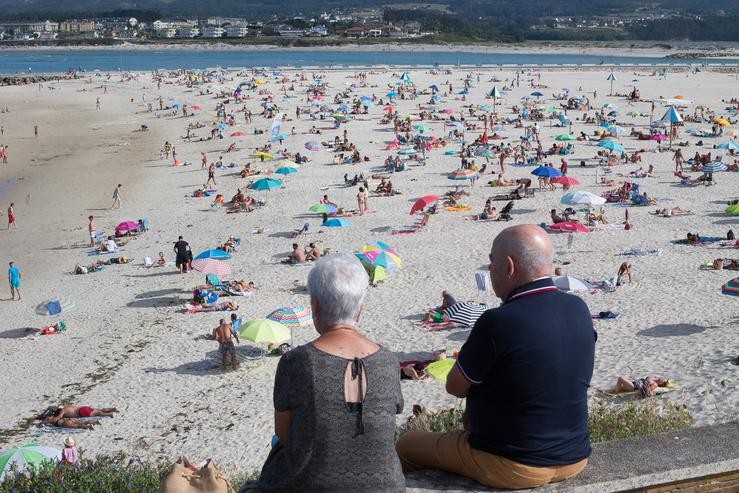 Dúas persoas observan a praia na Mariña (Lugo