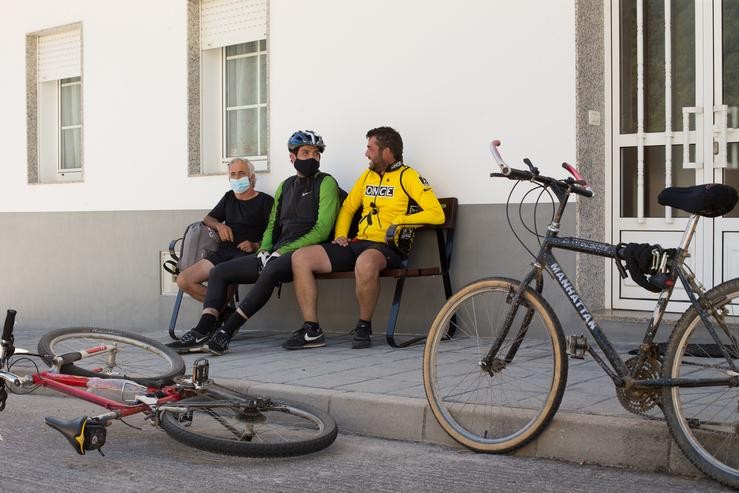 Os irmáns Primi (d) e Mario (c) e o seu tío Pedro (i), descansan xunto ás súas bicicletas nun banco da localidade de Triacastela, fin da súa etapa diaria, mentres os peregrinos retornan ao Camiño francés da Ruta Xacobea  /  Europa Press - Arquivo