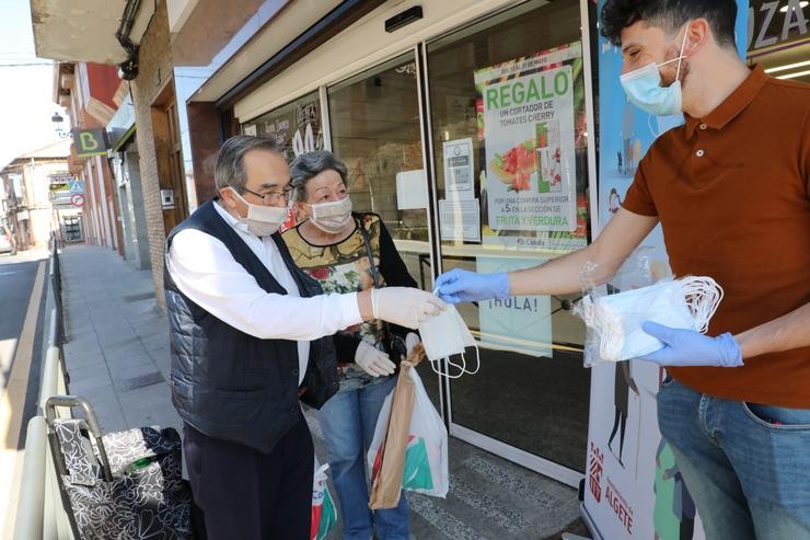 Repartición a dous clienes de máscaras á porta dun supermercado 