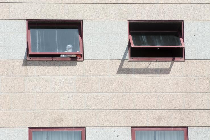 Un traballador protexido é visto por un dos cristais da residencia de maiores DomusVi de Outeiro de Rei en Lugo.. Carlos Castro - Europa Press / Europa Press