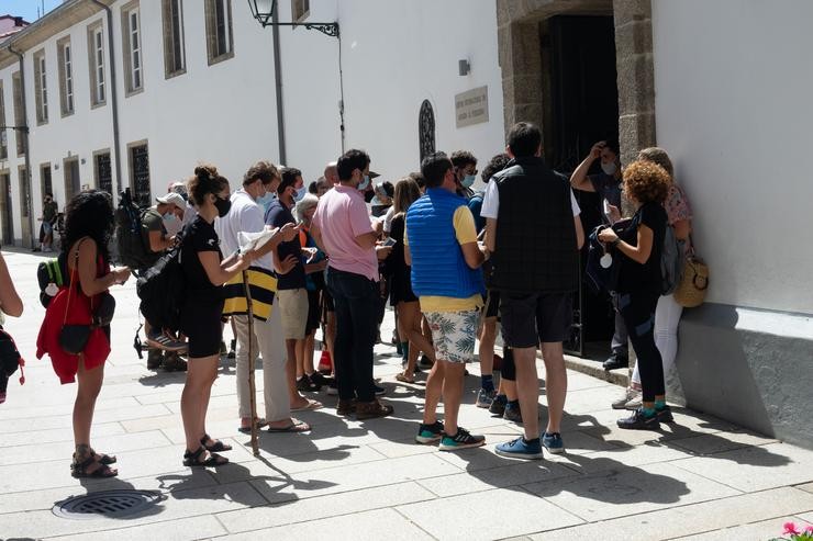 Peregrinos con máscaras  esperando a súa quenda para entrar nun albergue