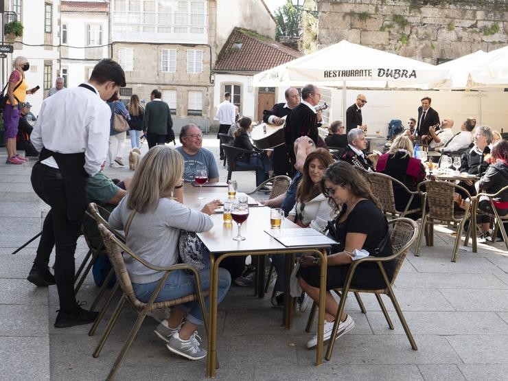 Un grupo de turistas consulta unha carta na terraza dun bar en Santiago de Compostela.. César Arxina - Europa Press / Europa Press