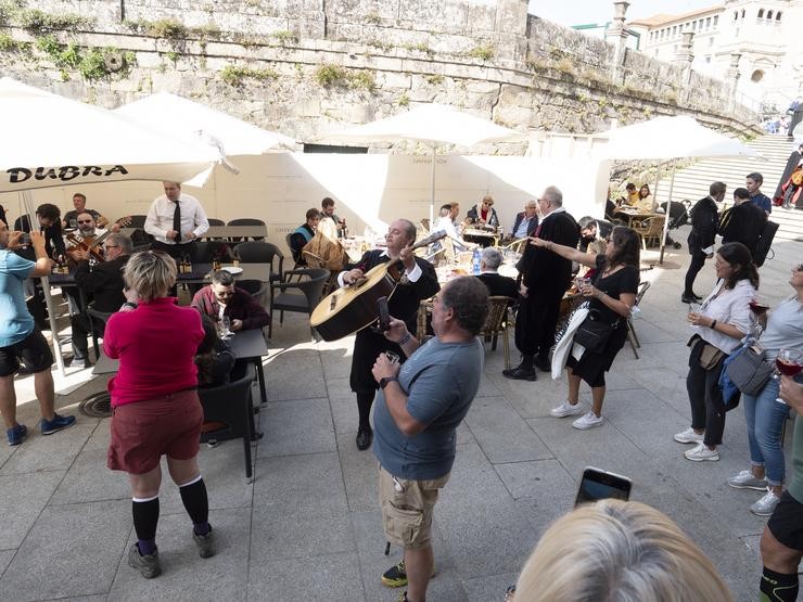 Un grupo de turistas canta cunha tuna nunha praza de Santiago de Compostela 
