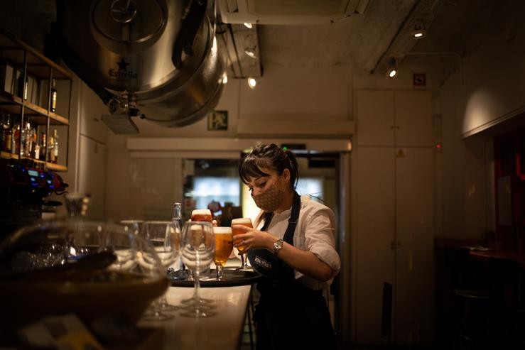 Unha camareira serve unha cervexa no interior dun bar nunha rúa céntrica de Barcelona. David Zorrakino - Europa Press / Europa Press