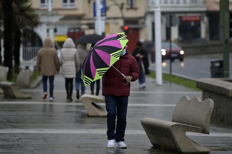 Un home cun paraugas camiña polo paseo marítimo mentres chove na Coruña. M. Dylan - Europa Press / Europa Press
