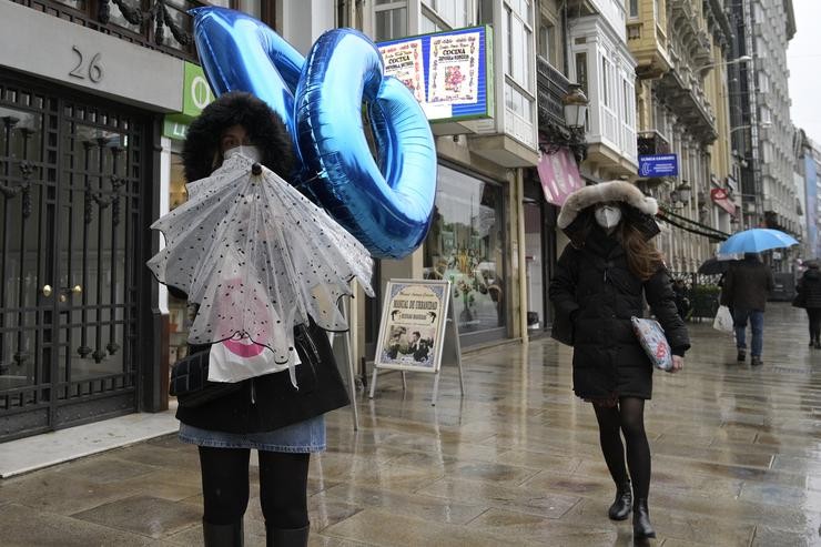 Transeúntes camiñan protexidos por unha vía da Coruña. M. Dylan - Europa Press 