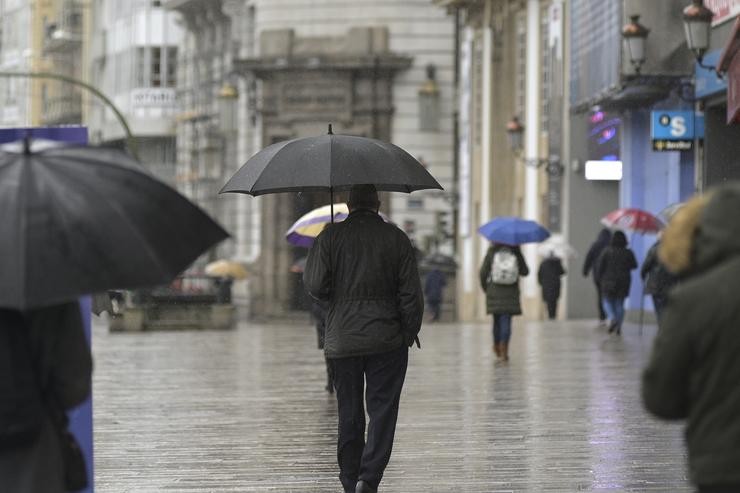 Transeúntes camiñan protexidos por unha vía da Coruña. M. Dylan - Europa Press 