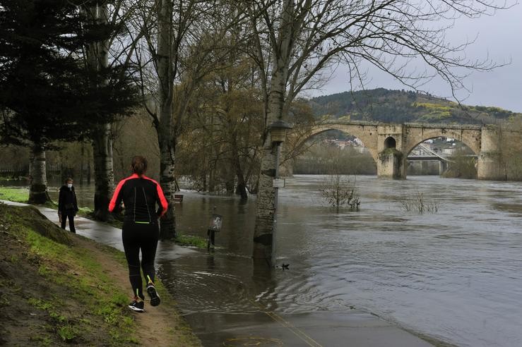 Varias persoas camiñan pola zona da praia da Antena alagada polo río Miño, en Ourense, Galicia (España), a 11 de febreiro de 2021. Rosa Veiga - Europa Press / Europa Press