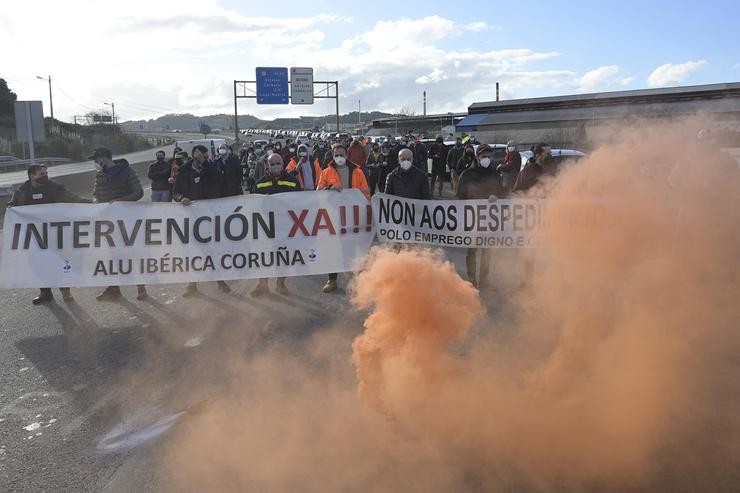 Concentración dos traballadores de Alu Ibérica que suxeitan dúas pancartas nas que se le: `Intervención Xa! Non aos Despedimentos´ diante da fábrica na Coruña 