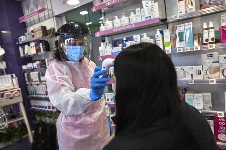 Unha farmacéutica toma a temperatura a unha muller antes de realizarlle un test de antíxenos nunha farmacia 