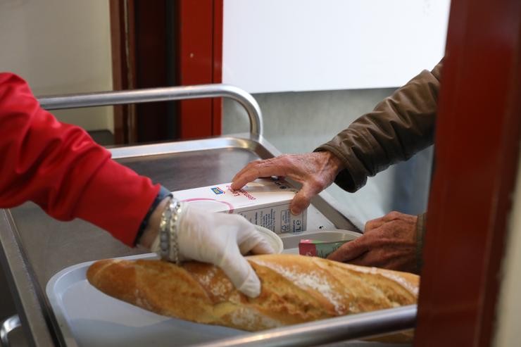 Un voluntario trae comida a unha persoa nunha repartición diaria de alimentos / Marta Fernández Jara - Europa Press