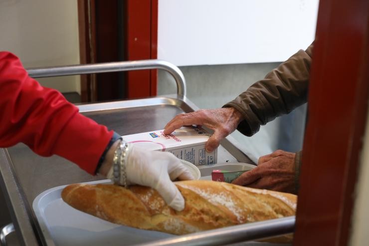 Un voluntario (i) trae comida a unha persoa (d) como parte da repartición diaria de alimentos do Comedor Social San José, en Ponte de Vallecas, Madrid (España), a 5 de febreiro de 2021.. Marta Fernández Xara - Europa Press 