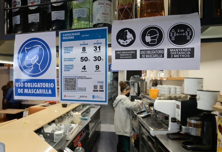 Varios carteis onde se mostra o aforamento e o código QR na porta dun restaurante na Coruña a 12 de marzo de 2021. M. Dylan - Europa Press / Europa Press