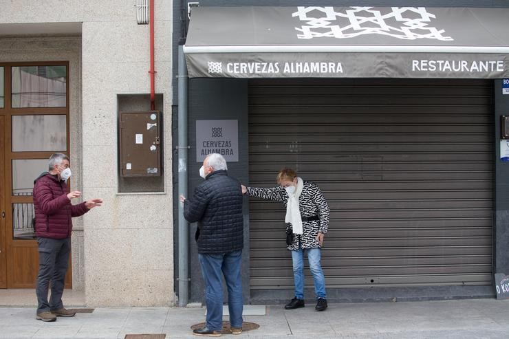 Dúas persoas conversan fronte a un bar coas persianas baixadas no municipio de Guitiriz, Galicia.. Carlos Castro - Europa Press / Europa Press