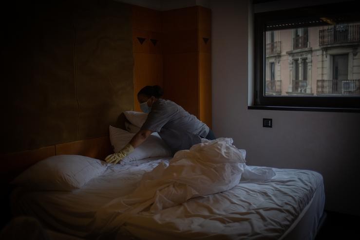 Unha camareira de pisos cambia as sabas dunha cama dunha habitación dun hotel 