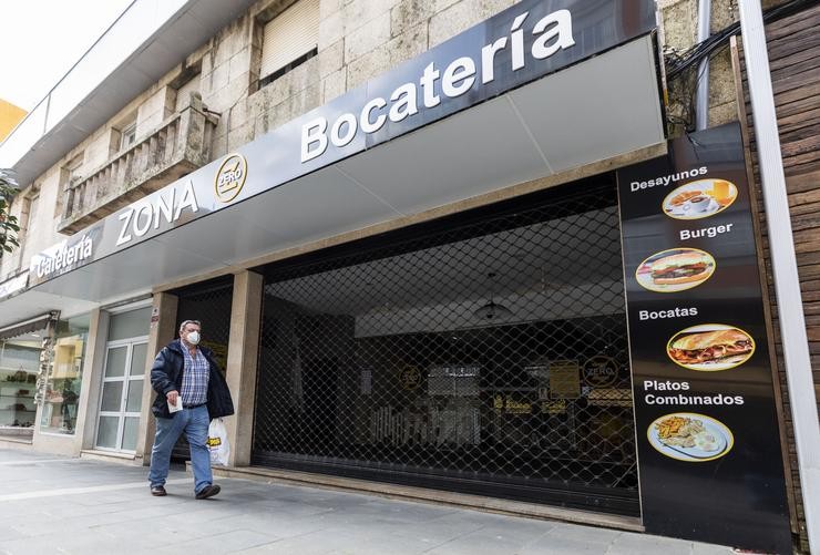 Un home camiña fronte a unha cafetaría pechada no Grove, o día en que entra en vigor o peche perimetral do municipio, a 8 de abril de 2021, en Pontevedra, Galicia, (España).. Beatriz Ciscar - Europa Press / Europa Press