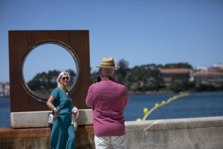 Un home bota unha foto a unha muller no paseo marítimo da praia de Sanxenxo. Beatriz Ciscar - Europa Press 