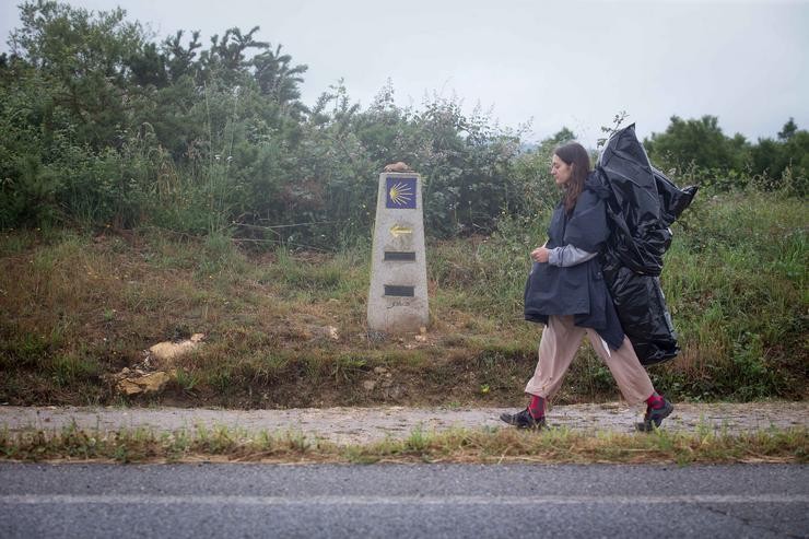 Unha peregrina camiña cara a Santiago de Compostela por onde transcorre o Camiño de Santiago francés 
