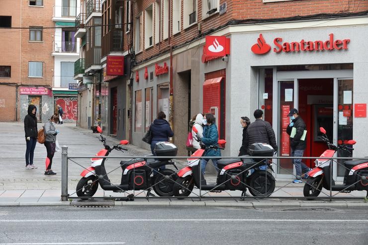 Varias persoas agardan para entrar nunha oficina do Banco Santander durante o inicio da cuarta semana do estado de alarma decretado a consecuencia do coronavirus, a 6 de abril de 2020 