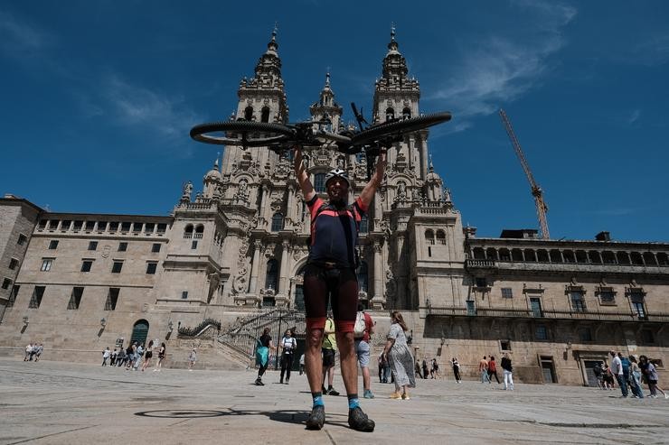 Un peregrino portugués levanta a súa bicicleta ao finalizar o Camiño de Santiago, fronte á Catedral de Santiago, a 6 de xuño de 2021 