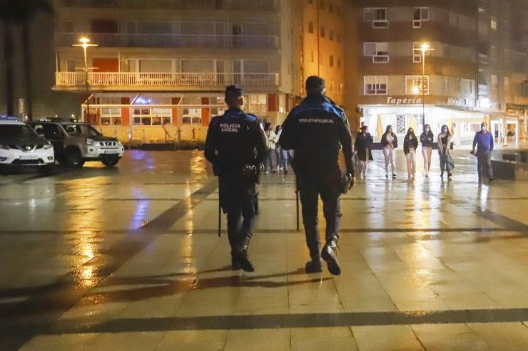 Dous axentes de Policía Local pasean polo porto de Sanxenxo para informar en cada un dos locais de lecer nocturno sobre as novas medidas Covid, a 3 de xullo de 2021 