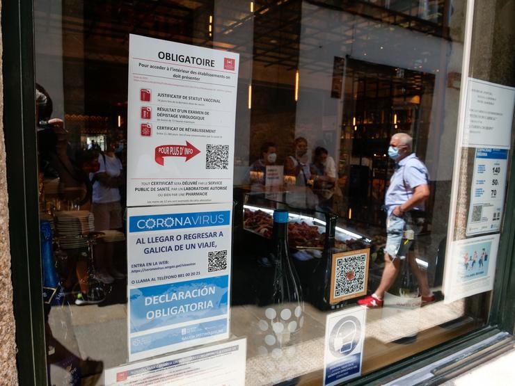 Carteis en diferentes idiomas de indicacións de obrigatoriedade de presentar certificados antes de acceder ao interior, nunha marisquería da Rua do Franco, en Santiago.. César Arxina - Europa Press 